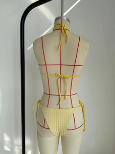 Detalle de bikini amarillo con textura de panal y diseño de lazos ajustables en espalda