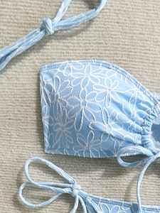 Light blue bikini set with white floral embroidery and ruffled edges in a flat lay view