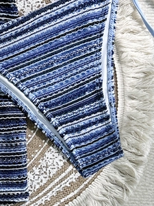 Detailed macro view of blue striped crochet bikini bottoms with side tie and white piping
