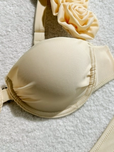 Detailed close-up of cream bikini top with elegant 3D rose floral strap ornament