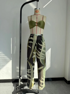 Detail of olive green ruched top with resin ring and tropical leaf print mesh pants