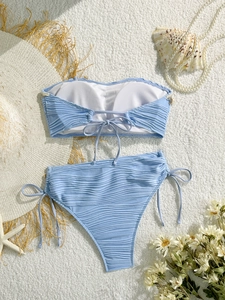 Dettaglio bikini a coste azzurro con top a fascia e decorazioni di conchiglie marine
