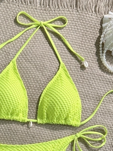 Detail of neon green crochet bikini top with white sea shells and halter neck ties