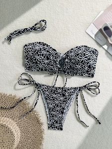 Flat lay of daisy print bikini set with sun hat and sunglasses on summer background