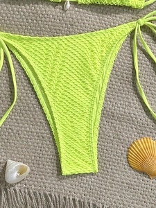 Detail of neon yellow mesh bikini bottom with side ties and decorative sea shells