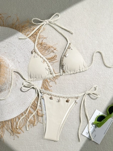 Detailed view of beige ribbed bikini with woven lace trim and seashell charms