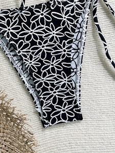Detail of black bikini bottom with white daisy print and adjustable side ties