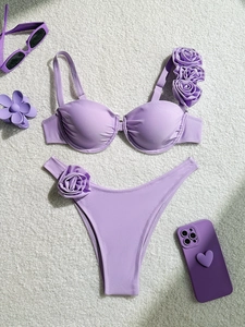 Detailed view of lavender bikini with 3D floral accents and underwire top on plush background