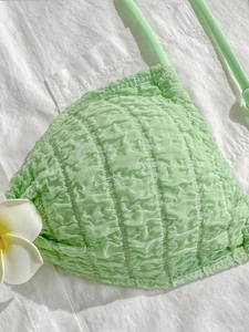 Close-up of mint green bikini top with seersucker texture and white flower detail