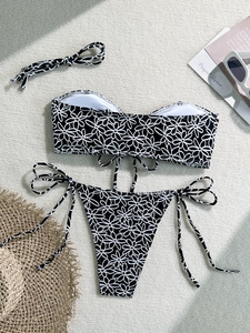 Flat lay of floral bikini set with side-tie bottoms and sunglasses on a woven rug