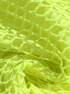 Macro view of neon yellow mesh fabric with hexagonal pattern and matching lining