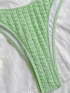 Macro detail of light green smocked fabric on bikini bottom with white inner lining