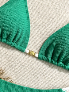 Green ribbed bikini set with shell metal detail laid on beige woven background