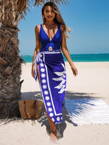 Detail of navy one-piece swimsuit with metal shell buckle and floral beach sarong wrap