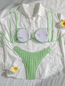Flat lay of mint green crinkled bikini set with frangipani flowers for summer beach vacations