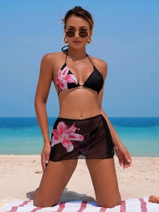 Three-piece black floral bikini set with halter top and matching sheer mesh beach skirt