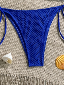 Macro view of blue mesh crochet bikini bottoms with side ties on a beach-themed background