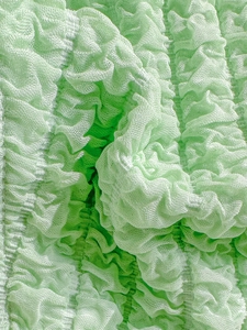 Close-up of light green smocked fabric with mesh texture for bikini swimwear