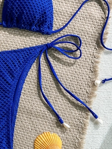 Close-up of royal blue mesh bikini with decorative white shell charms on tie strings