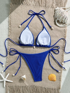 Flat lay of royal blue crochet bikini set with natural shells and beach accessories