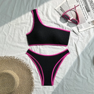 Detailed view of black textured one-shoulder bikini with pink contrast trim and high waist