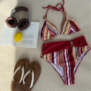 Flat lay of a striped bikini set with high-waist bottoms on a resort-style beach mat