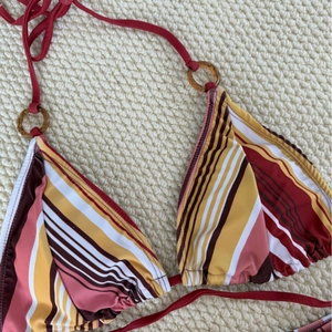 Detail of striped triangle bikini top with amber ring and multi-color patterns