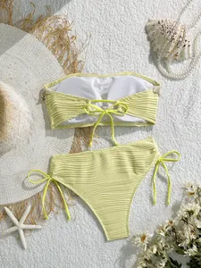 Flat lay di bikini giallo pallido con texture a conchiglia e accessori da spiaggia