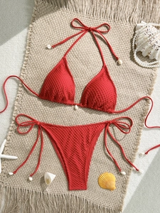 Detail view of red crochet bikini with halter neck ties and small seashell accents