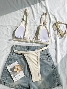 Zweiteiliger gerippter weißer Bikini mit Schildpattringen und Denim-Shorts auf Leinen
