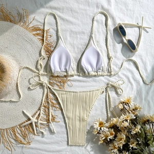 Detailed macro view of off-white ribbed bikini fabric with shell details and side ties