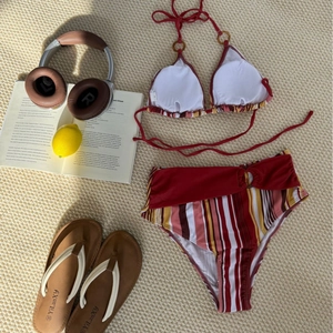 Flat lay of striped bikini set with ring details and vibrant summer vacation props
