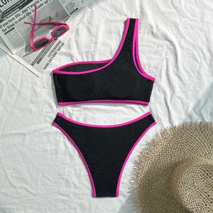 Detail of black textured one-shoulder bikini top with neon pink piping and summer props