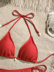 Detail of red mesh bikini top with halter neck ties and decorative white shells