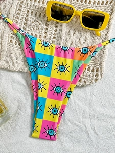 Summer bikini bottom with pop art checkerboard print and eye pattern on a beach setting