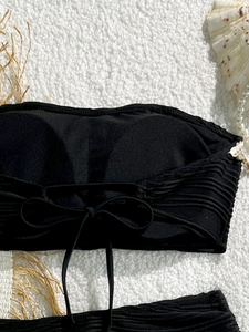 Dettaglio del top bikini a fascia nero con tessuto a coste e fiocco sul retro