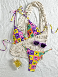Close-up of colorful checkerboard and eye print bikini set with stylish summer accessories