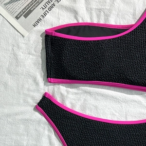 Detail of black textured seersucker bikini with neon pink contrast piping and modern design