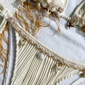 Detail of off-white ribbed bikini featuring real seashells and woven tassel accents