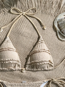 Detailed view of beige textured bikini with shell ornaments and scalloped edges