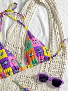 Detail view of a triangle bikini top featuring a checkerboard print and blue eye motifs