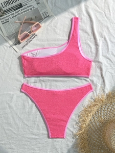 Detailed view of bright pink one-shoulder bikini set with seersucker textured fabric