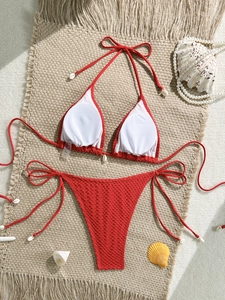 Detail of red mesh crochet bikini set with shell accents on a beach-themed background