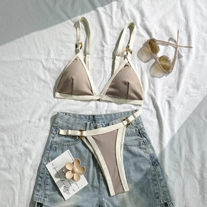 Detail eines beigen Ripp-Bikinis mit weißem Rand und schicken Schildpatt-Ring-Verbindern