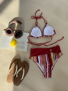 Red halter bikini top with retro striped high-waist bottoms laid on a beach mat