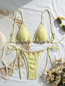 Close-up of yellow ribbed bikini featuring delicate seashell and starfish charms on edges