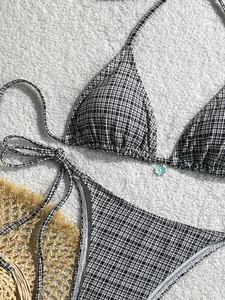Chic black and white gingham bikini set with daisy pendant on white fleece background