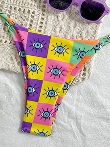 Close-up of printed bikini bottom with colorful checkerboard and eye patterns on white crochet