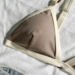 Detail eines gerippten Bikini-Oberteils mit Kontrastpaspel und Schildpatt-Ringen