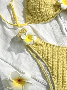 Solid yellow textured bubble fabric bikini set with halter top on white shirt background
